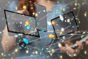 Une personne interagit avec des appareils numériques flottants - écran de bureau, smartphone et ordinateur portable - au milieu d'un réseau de points de données connectés, de chiffres et d'icônes technologiques abstraites.