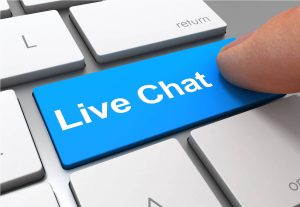 Un doigt appuyant sur la touche bleue "Live Chat" d'un clavier d'ordinateur, à côté de la touche retour.